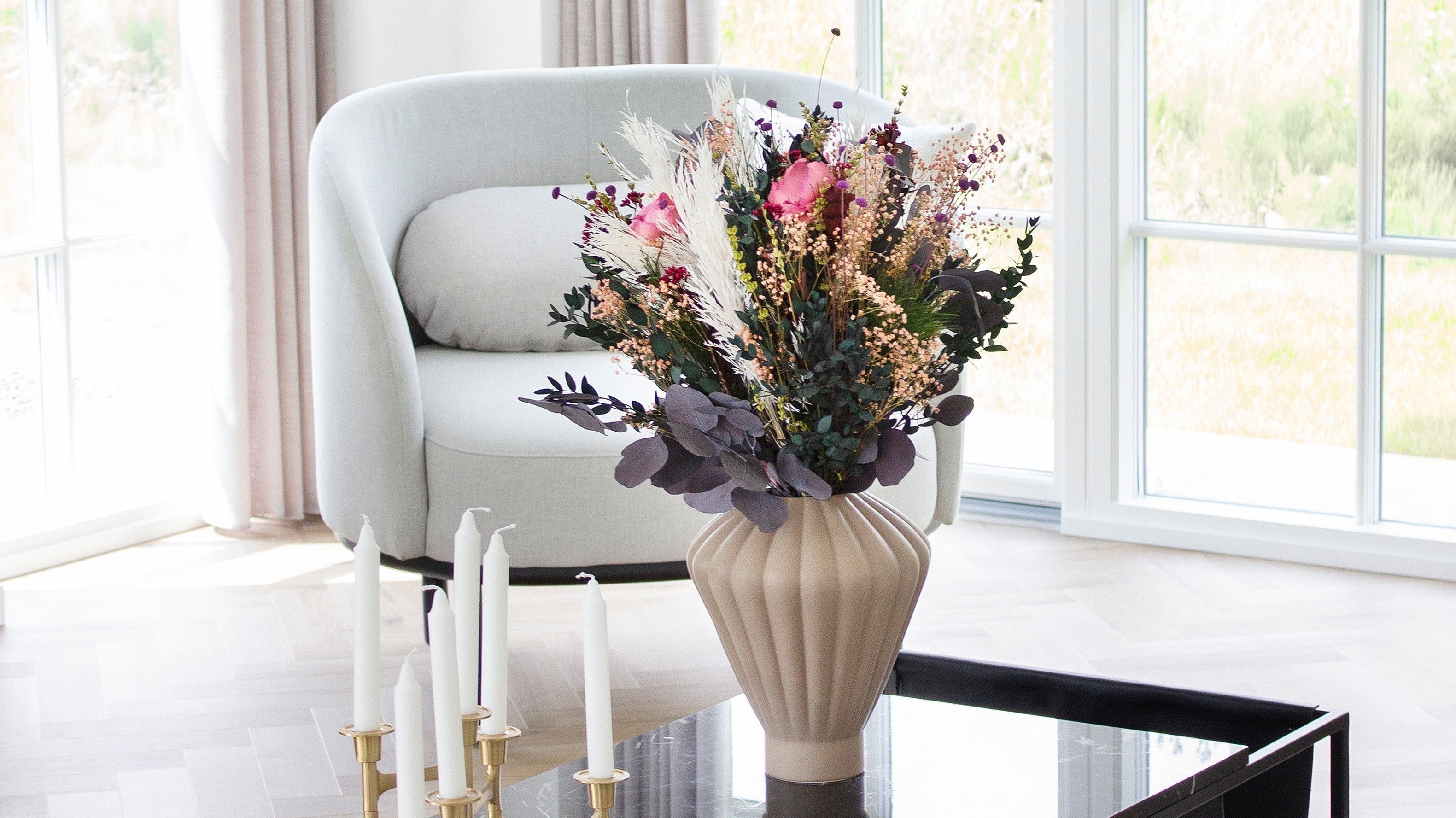 Bukett i keramikvas som står på ett vardagsrumsbord.