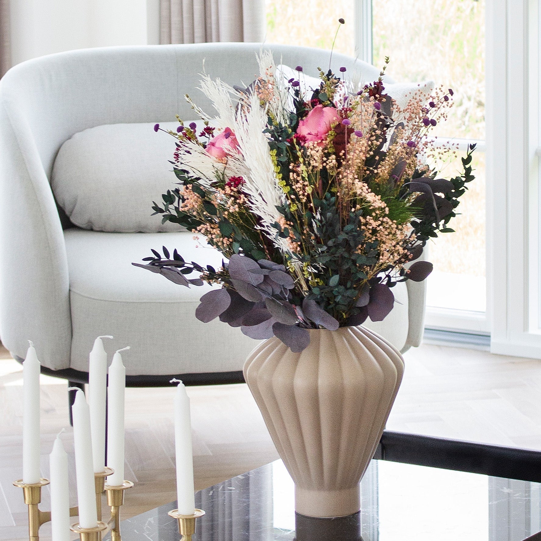 Bukett i keramikvas som står på ett vardagsrumsbord.