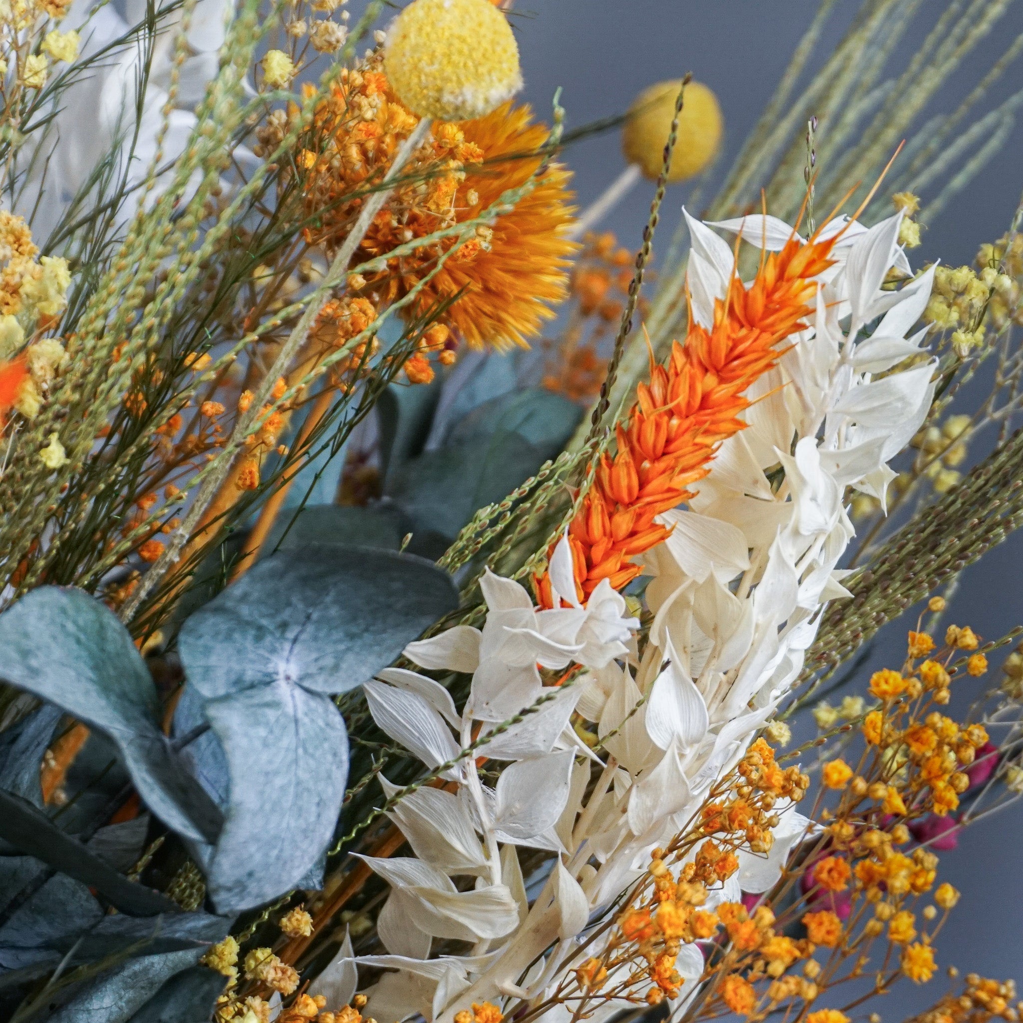Närbild av en säsongsinspirerad bukett med höstfärger – orange, gult, vitt och grönt