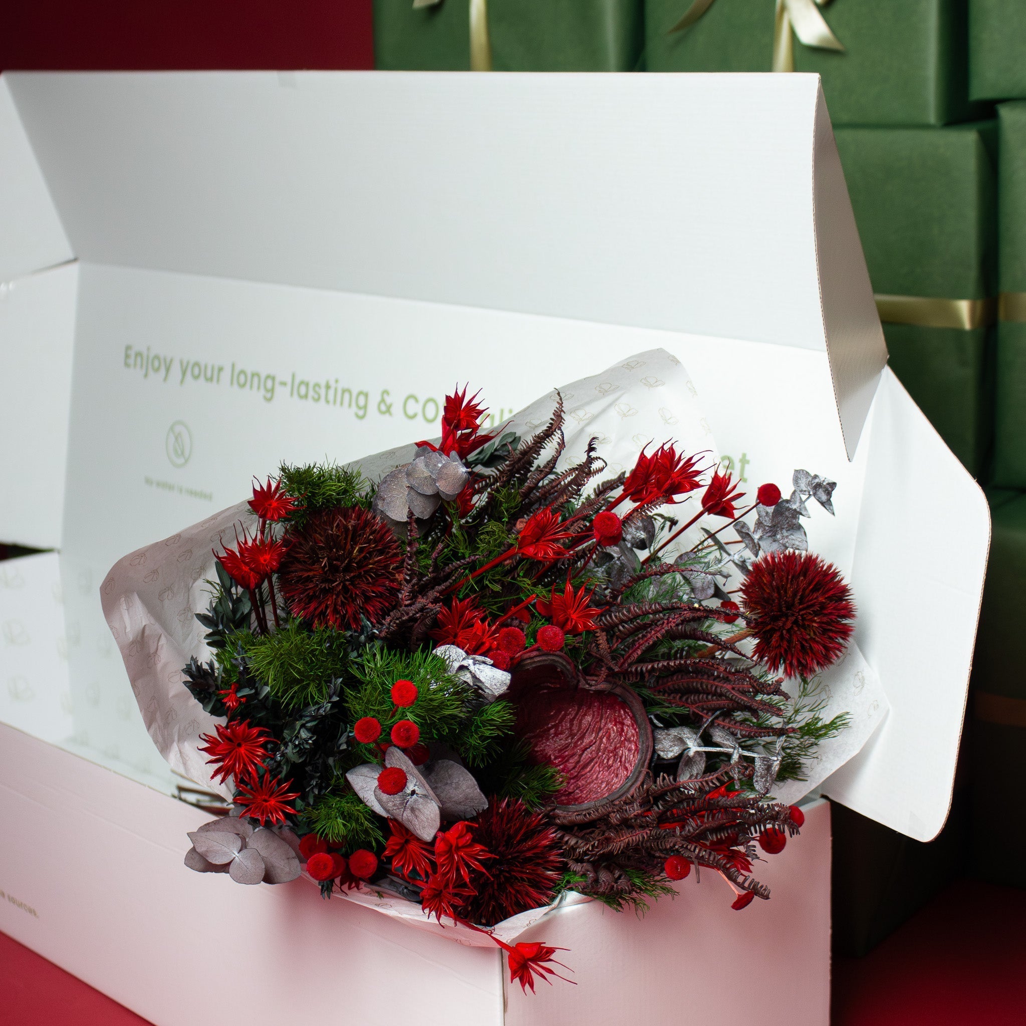 Detaljbild på en röd bukett omsluten av vitt silkespapper i en vit låda.