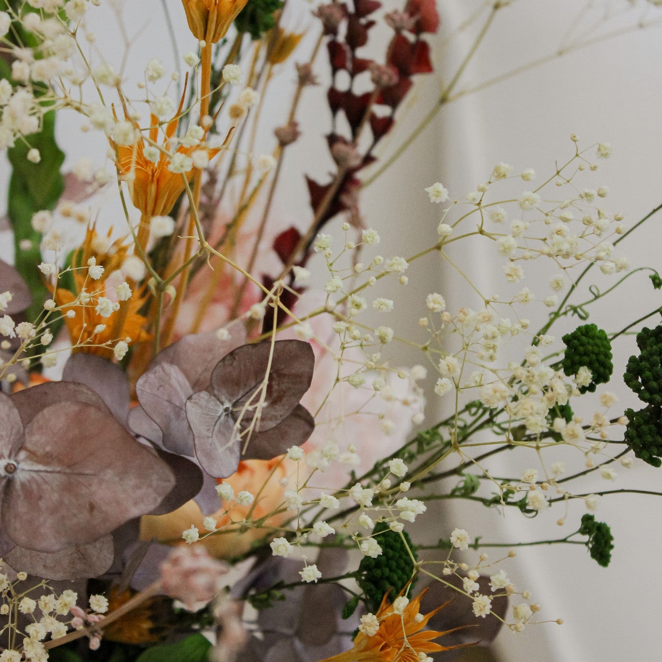 Närbild på en bukett med orange, bruna och gröna blommor