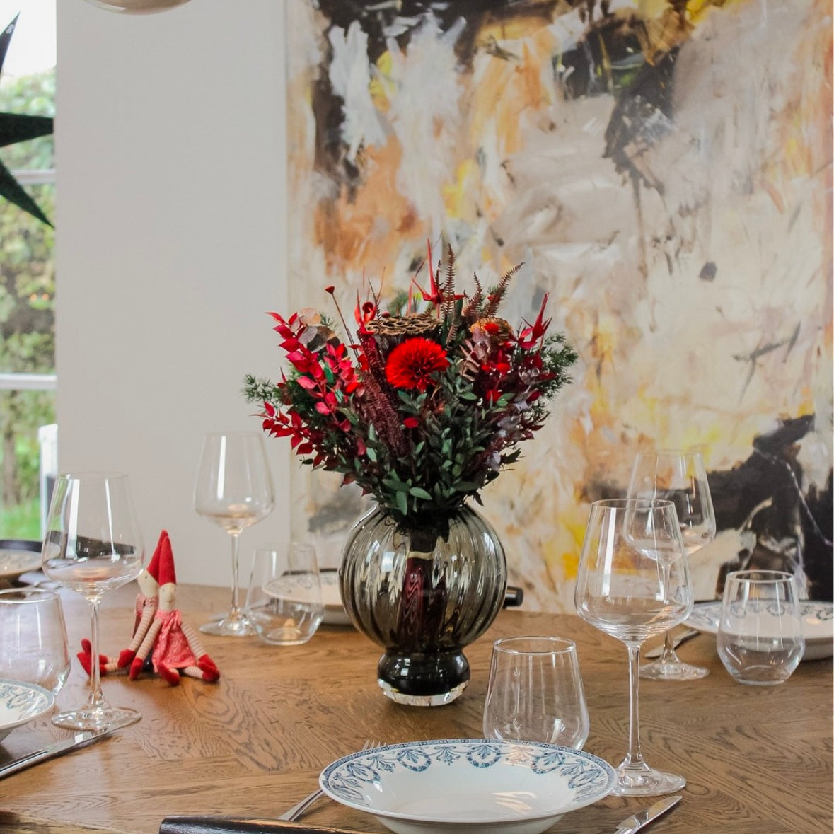 Dukat bord i jultema, prytt med en röd, julig bukett som mittpunkt