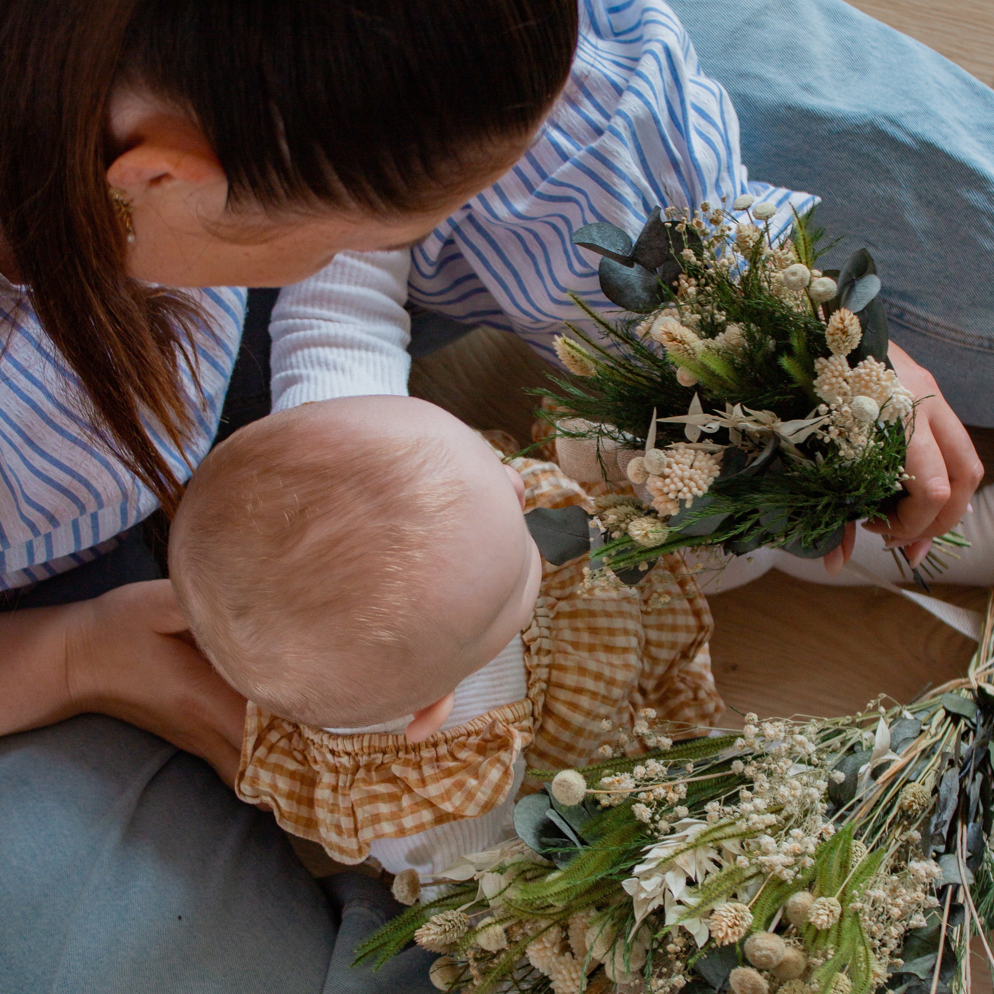 Mamma och litet barn sedda ovanifrån, håller i och tittar på buketten Mor & Barn.