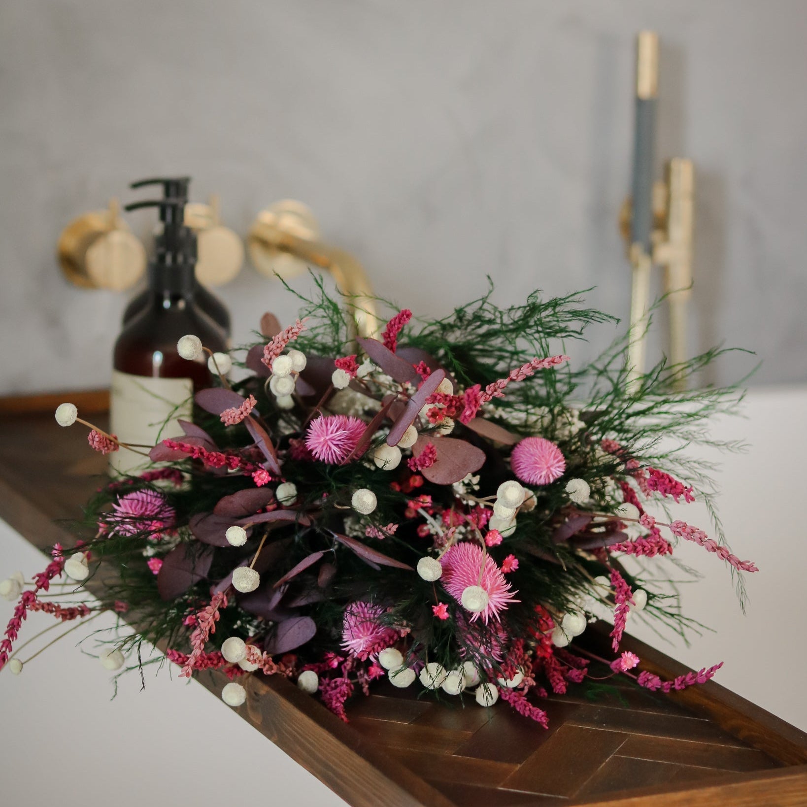 Elegant bukett i gröna och rosa nyanser vilar på badkarets kant.