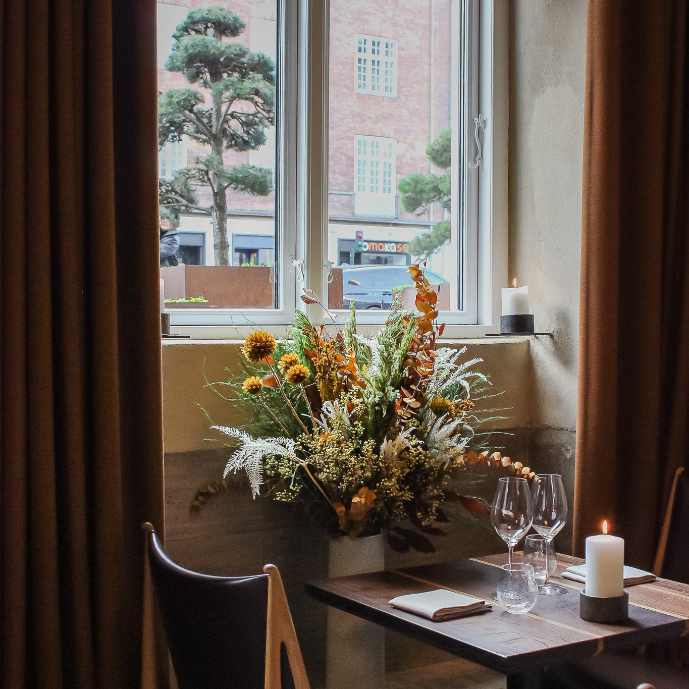 Stämningsfullt dukat bord på café med blomdekoration i dova höstfärger.