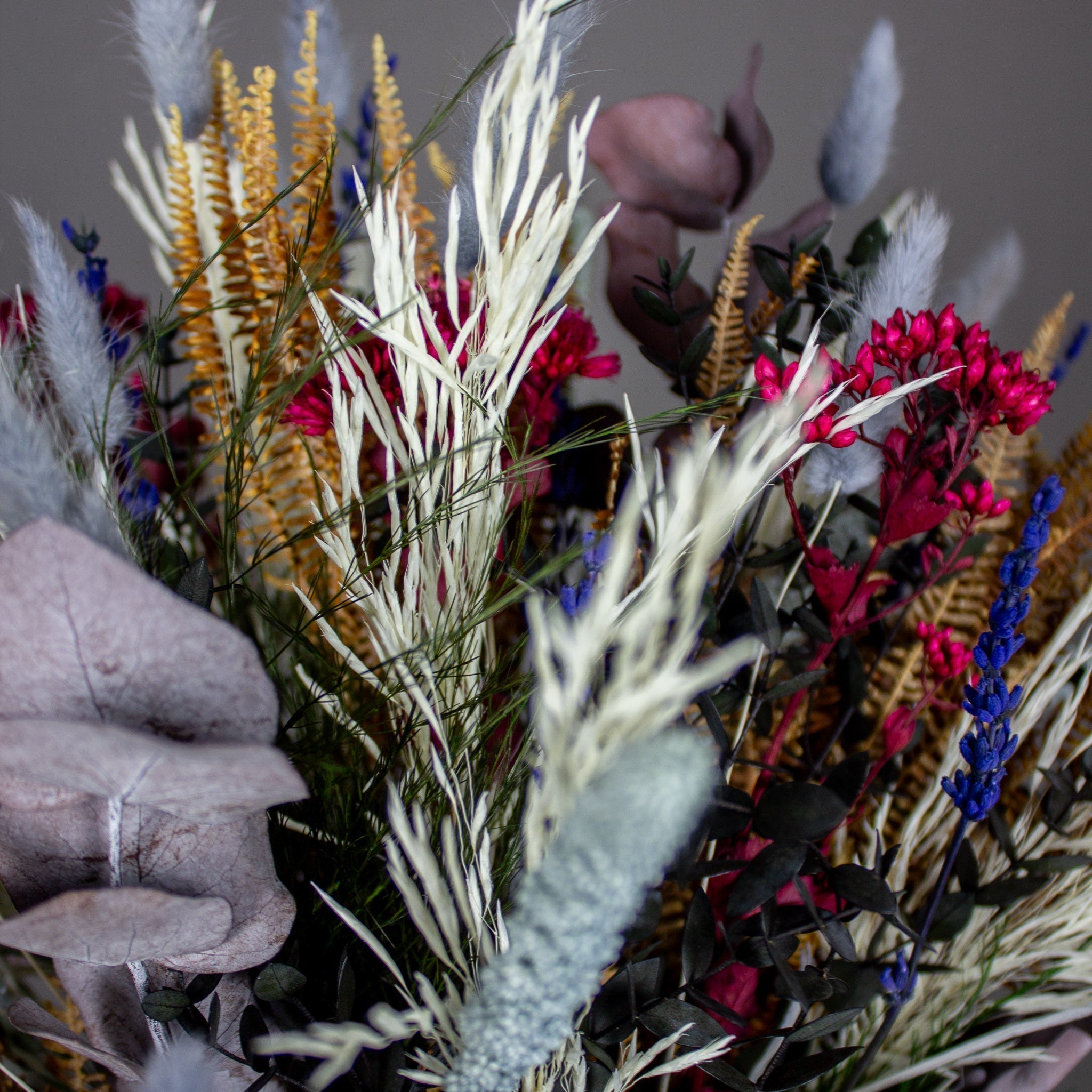 Detaljbild av en blomsterbukett med nyanser av vitt, orange, rosa och blått.