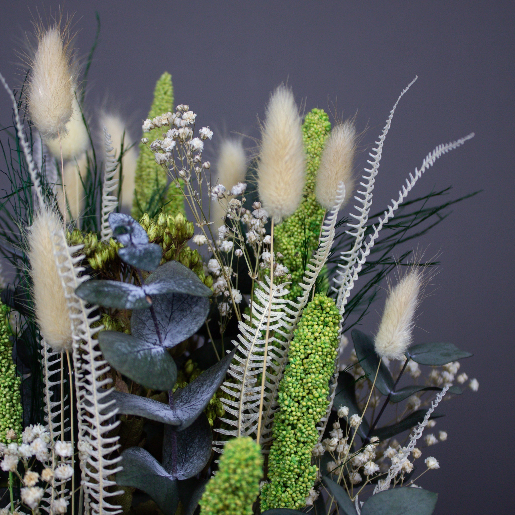 Nærbillede af en dekoration med grøn-hvide langtidsholdbare blomster.