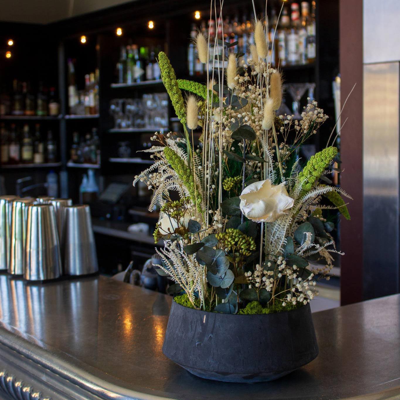 Närbild av blomdekoration i vitt och grönt som står på en bardisk på Hotel Vejlefjord