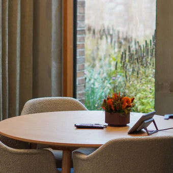 Liten orange blomdekoration står på ett runt bord i kontorsmiljö