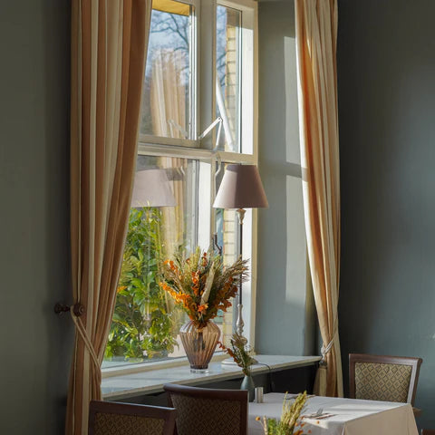 Litet middagsbord på hotell Vejlefjord dåar en bukett i orange och grönt pryder på fönsterbrädan