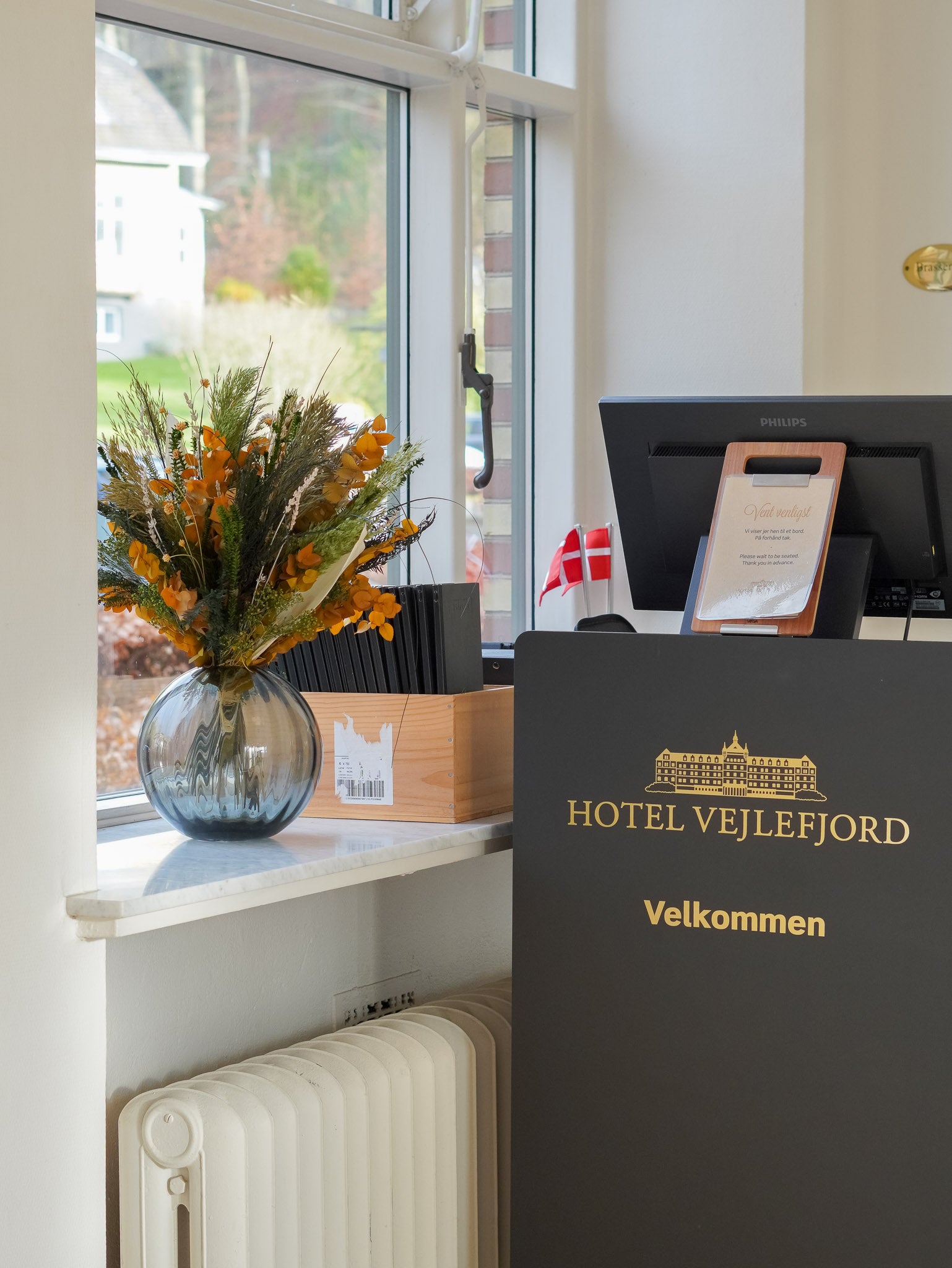 Orange och grön bukett som pryder på fönsterbrädan vid Hotel Vajlefjords check in disk för deras restaurant.