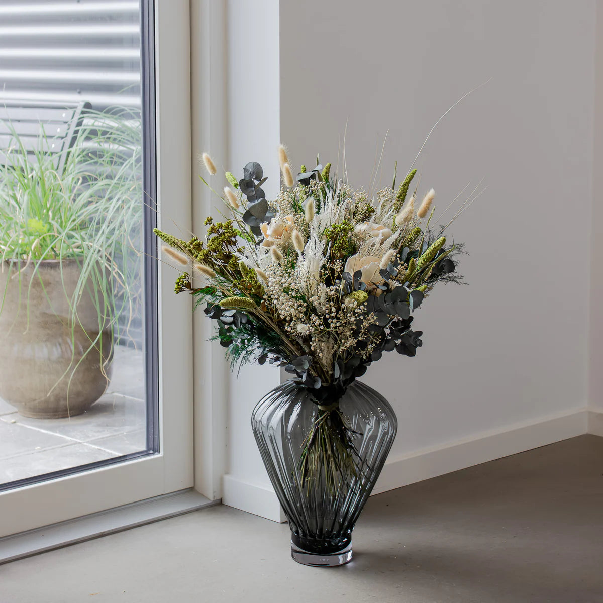 Bukett Grön Harmoni i gröna och vita nyanser i grå glasvas placerad på golvet.