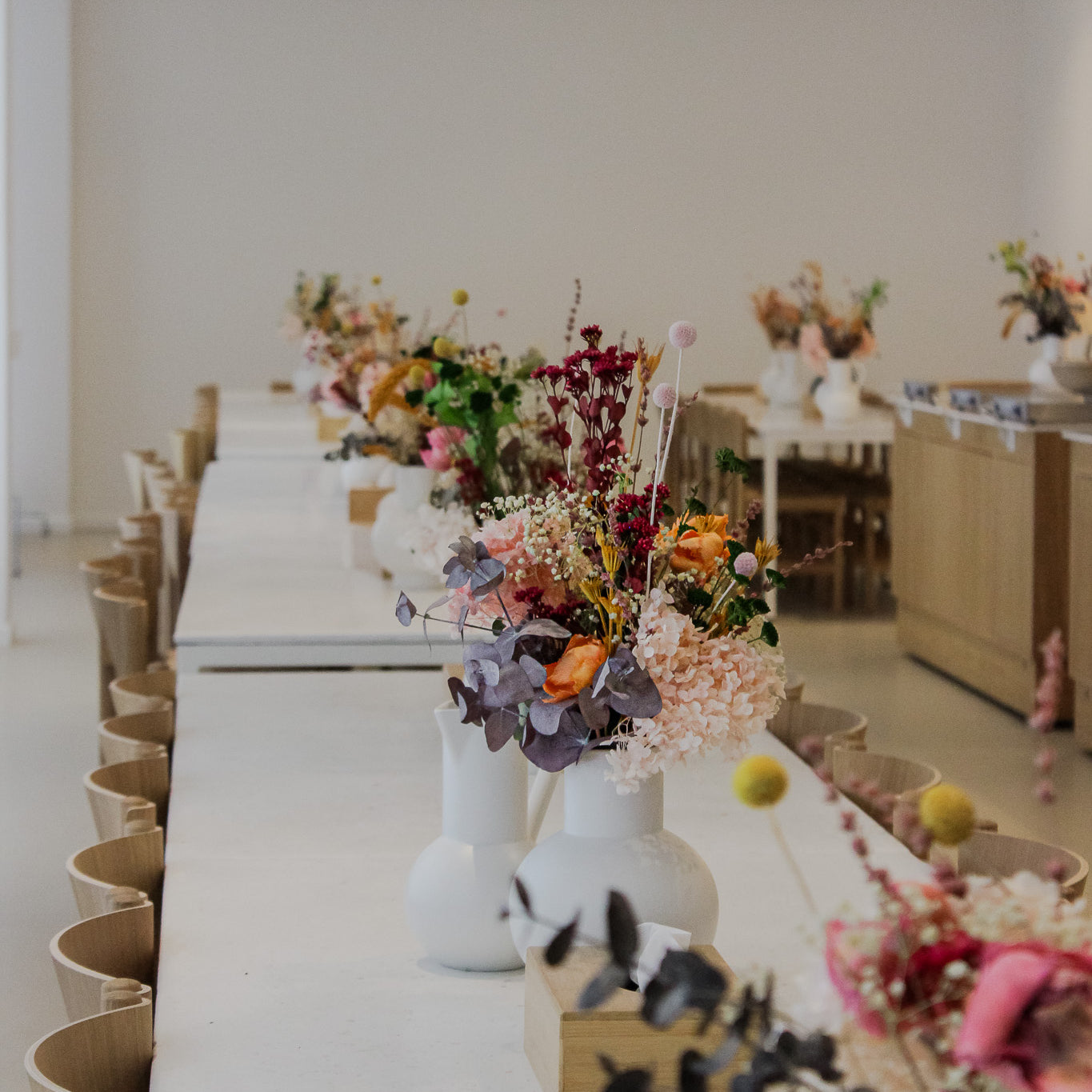 Vita långbord med vackra, färgglada blombuketter i vita vaser