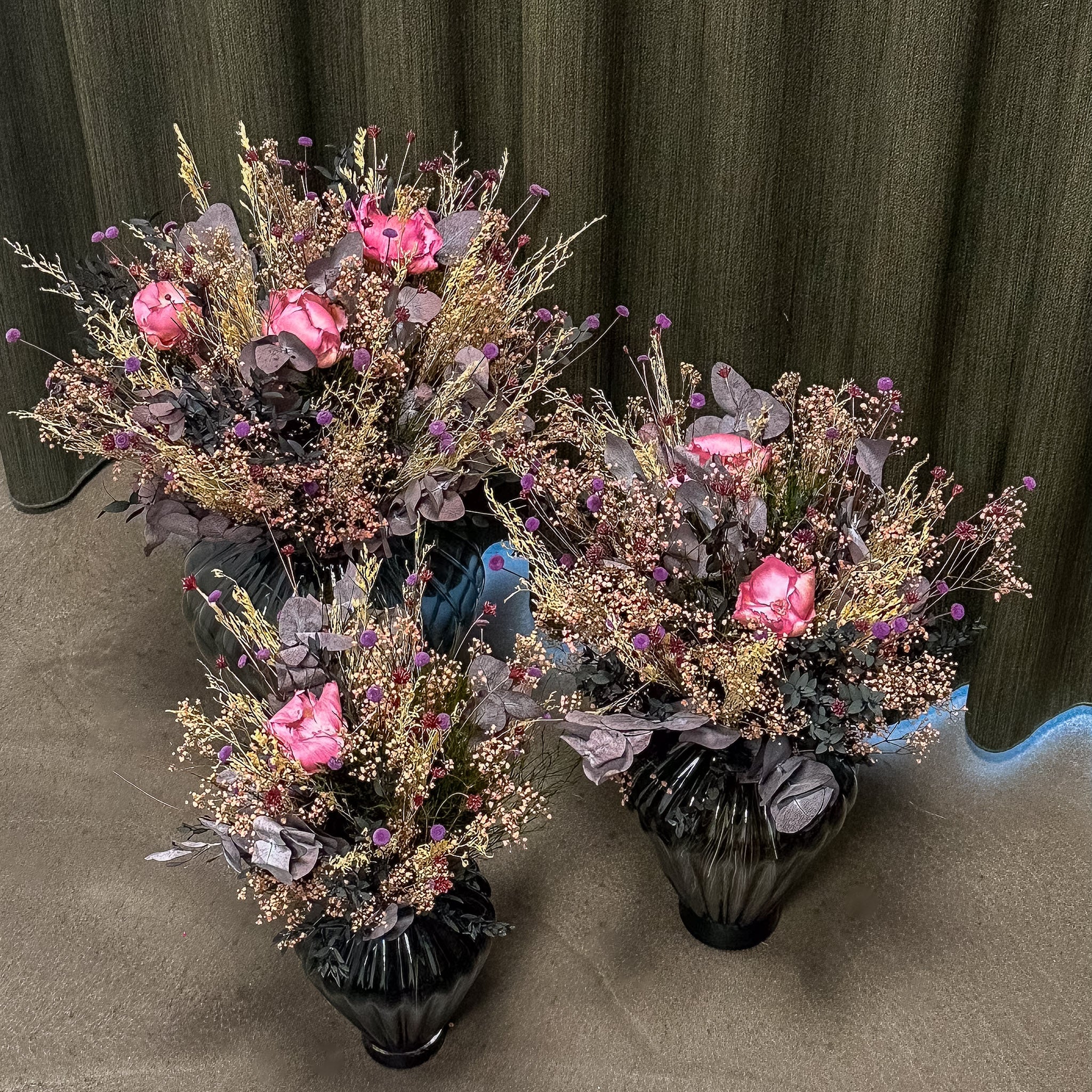 En vacker bukett i tre storlekar i rosa, vita och lila nyanser som står på golvet