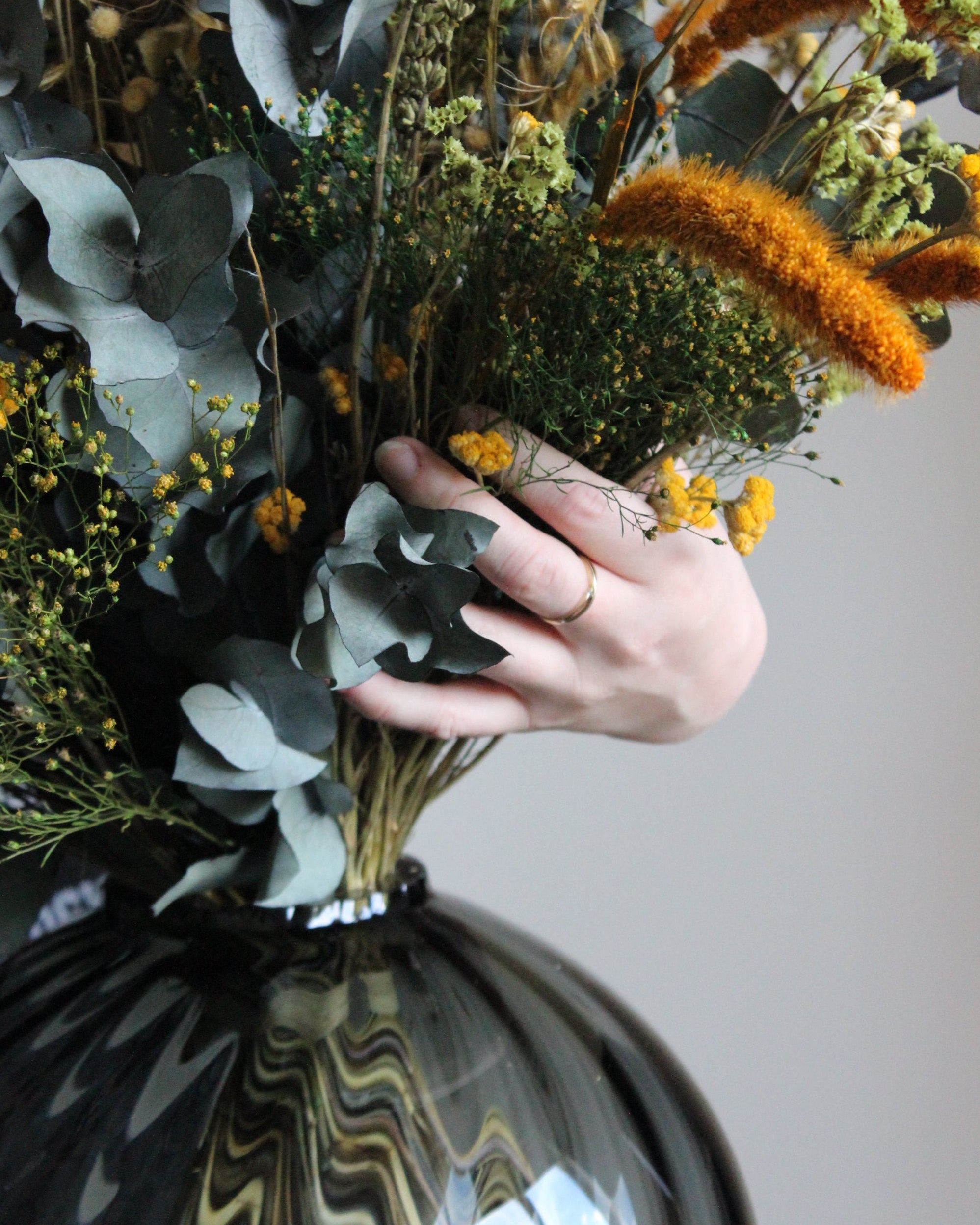 Hand som arrangerar en bukett blommor i en glasvas