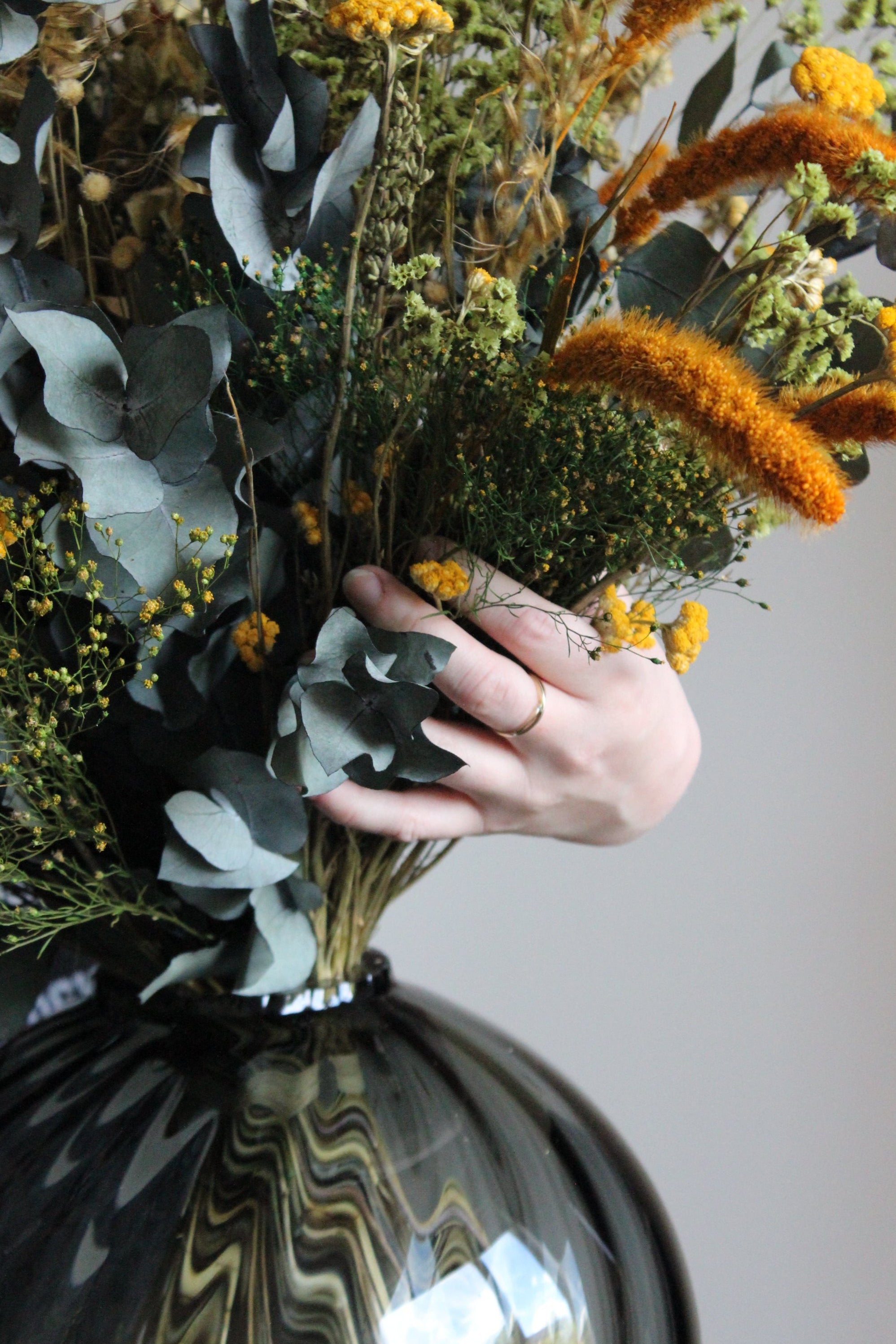 Hand som arrangerar en bukett blommor i en glasvas