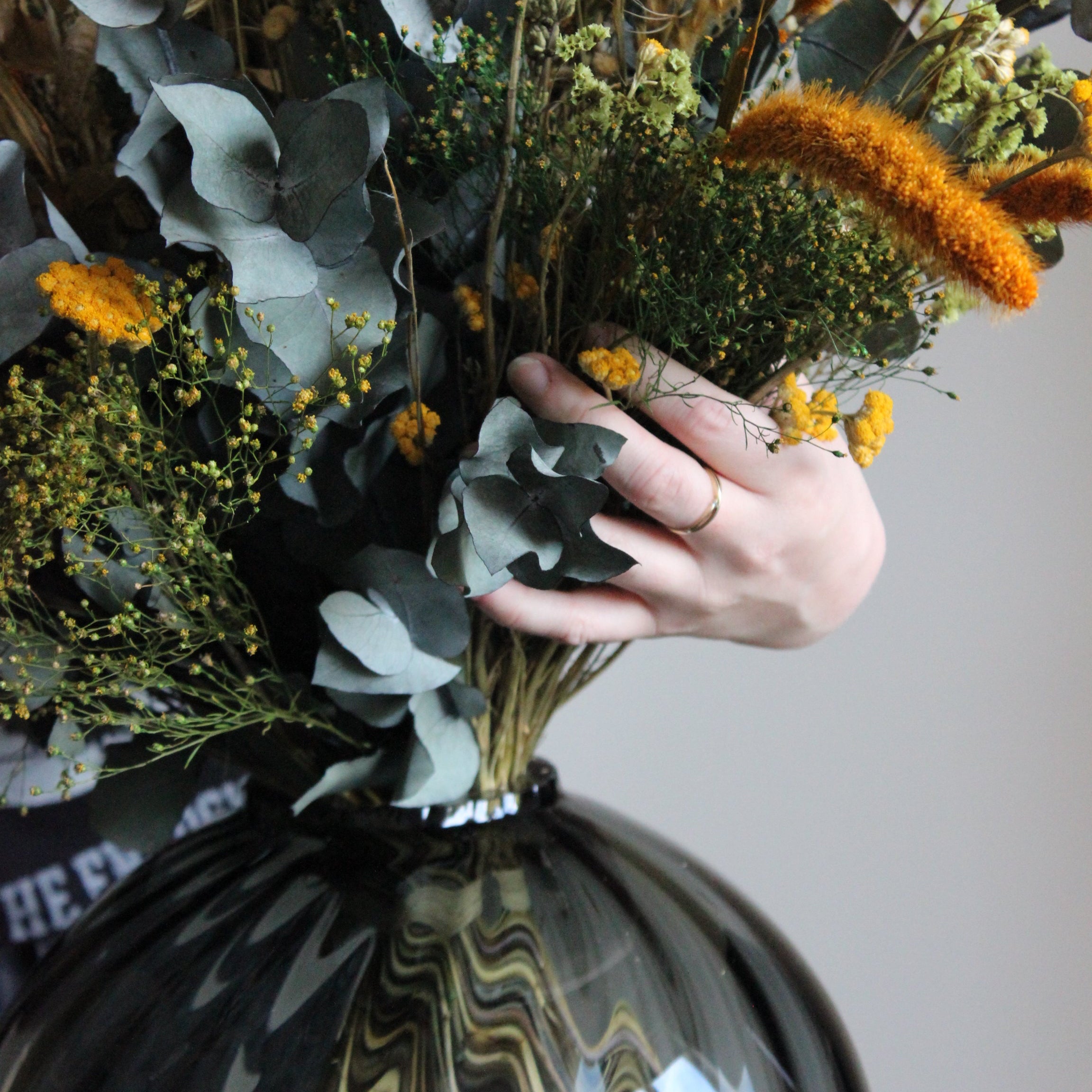 Hand som arrangerar en bukett blommor i en glasvas