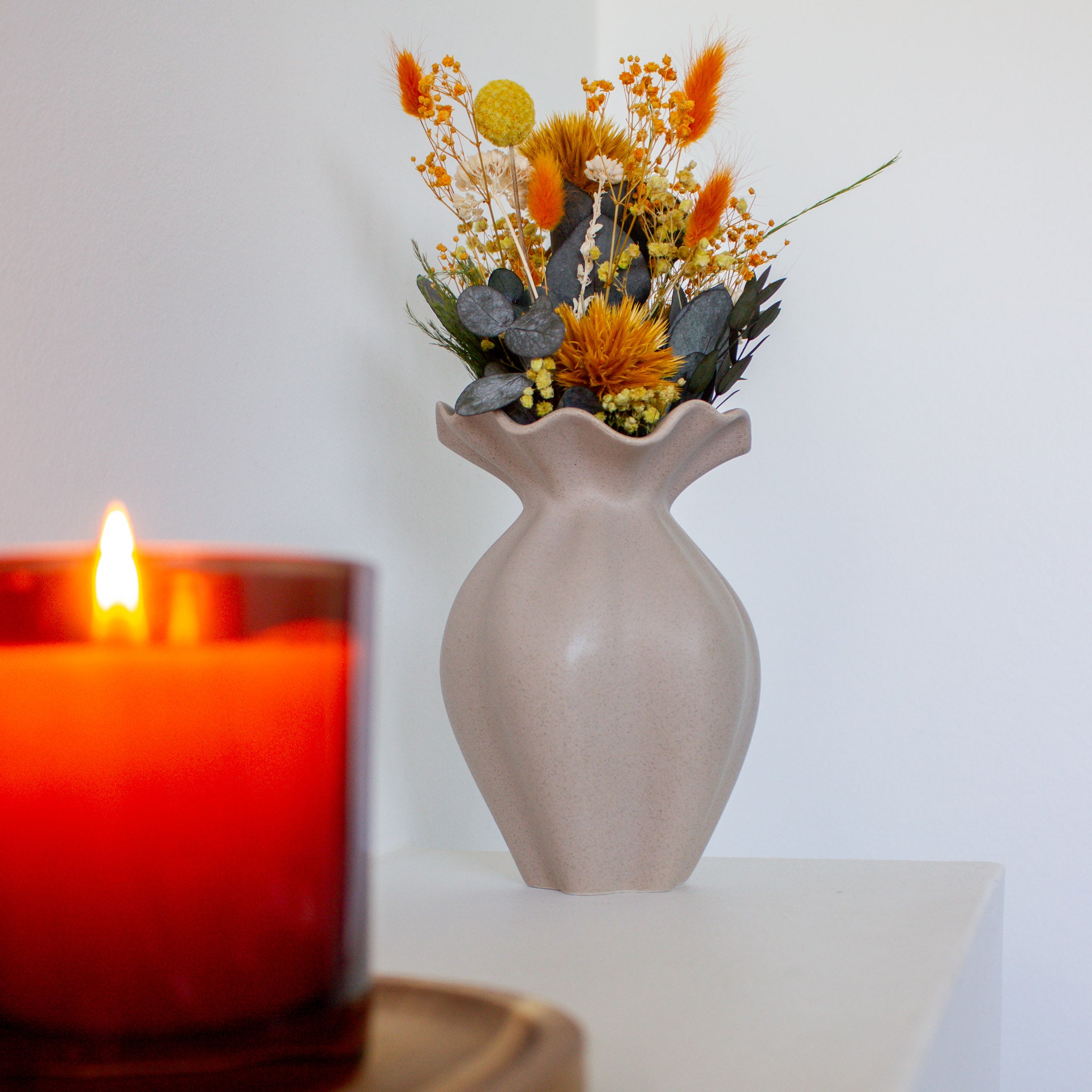 Närbild på en orange miniatyrbukett i en stilfull Nellie-vas.
