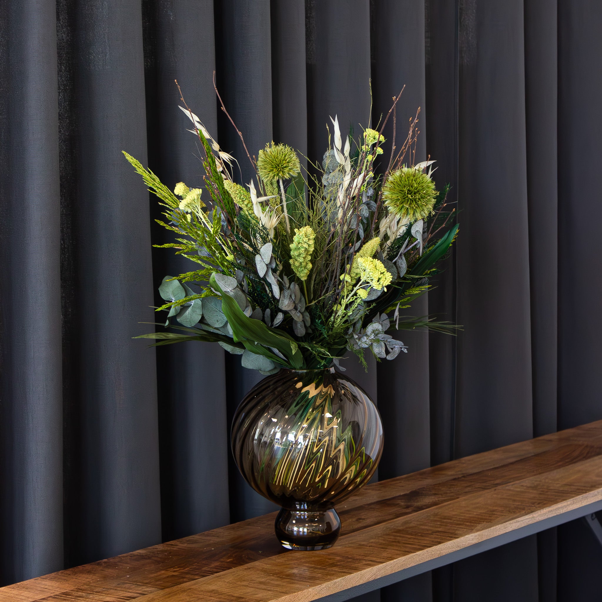 Rund glasvas med en grön bukett