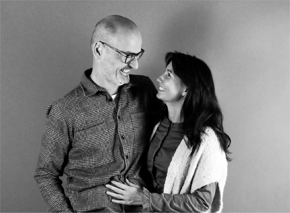 Svartvitt foto av Living Flowers grundare Henrik och Britta som tittar på varandra och ler