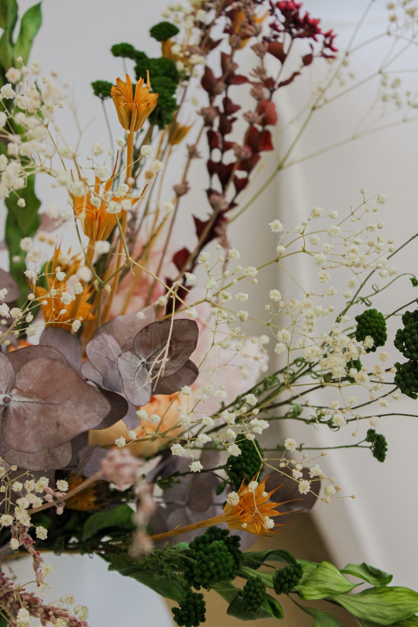 Närbild på en bukett med orange, bruna och gröna blommor