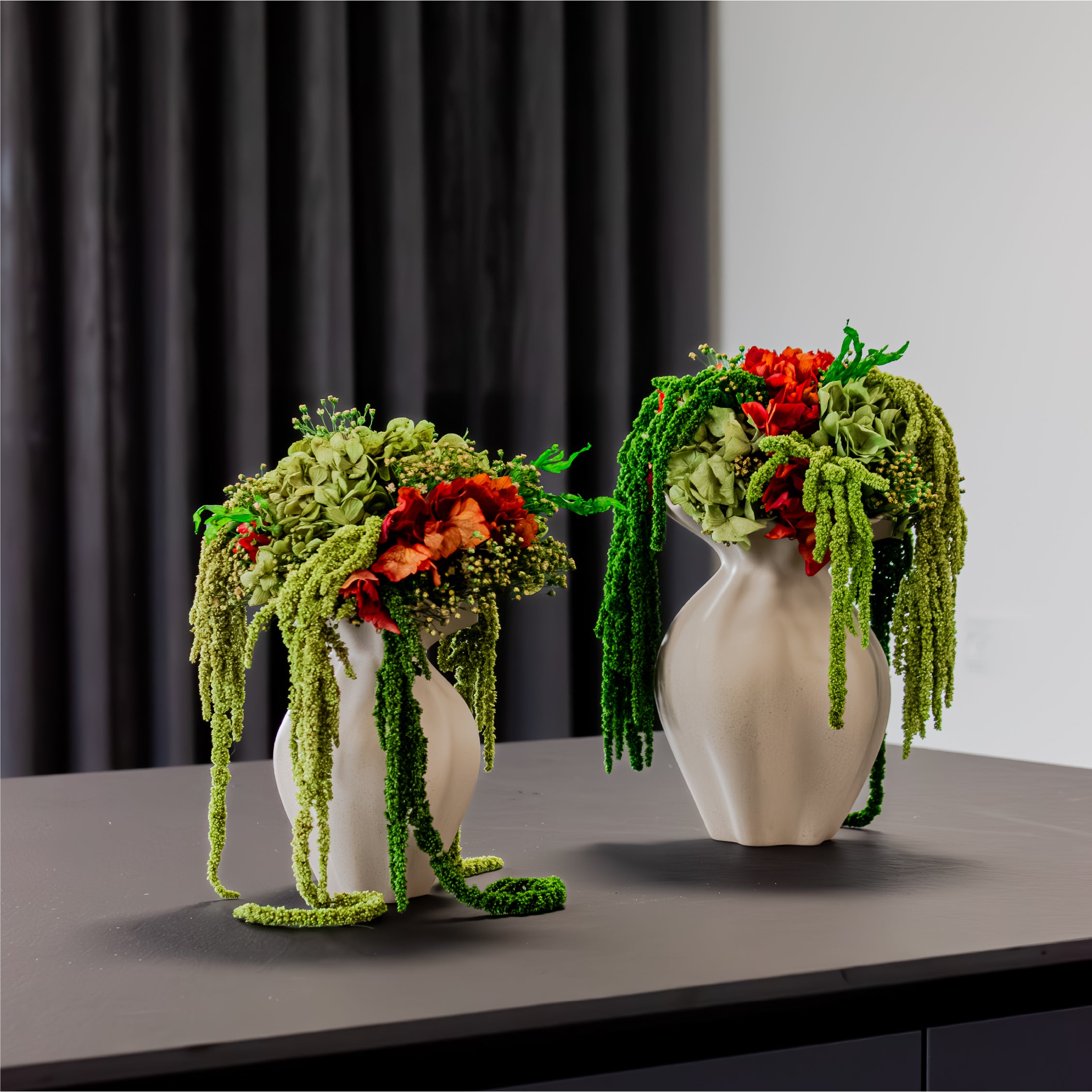 Två eleganta sandfärgade vaser av modellen Nellie, med gröna och orangea buketter.