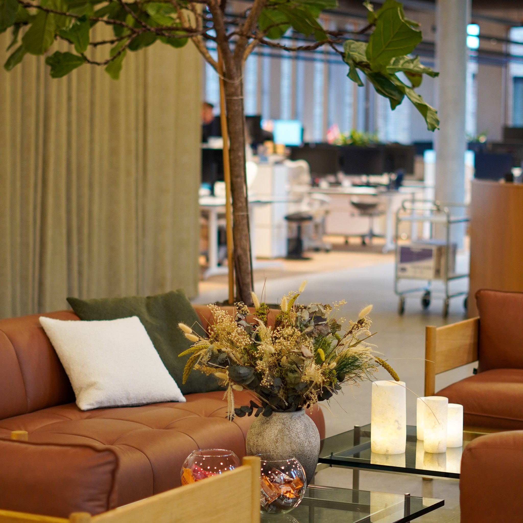 Lounge med soffor, fåtöljer och en blombukett som står på ett lågt bord.