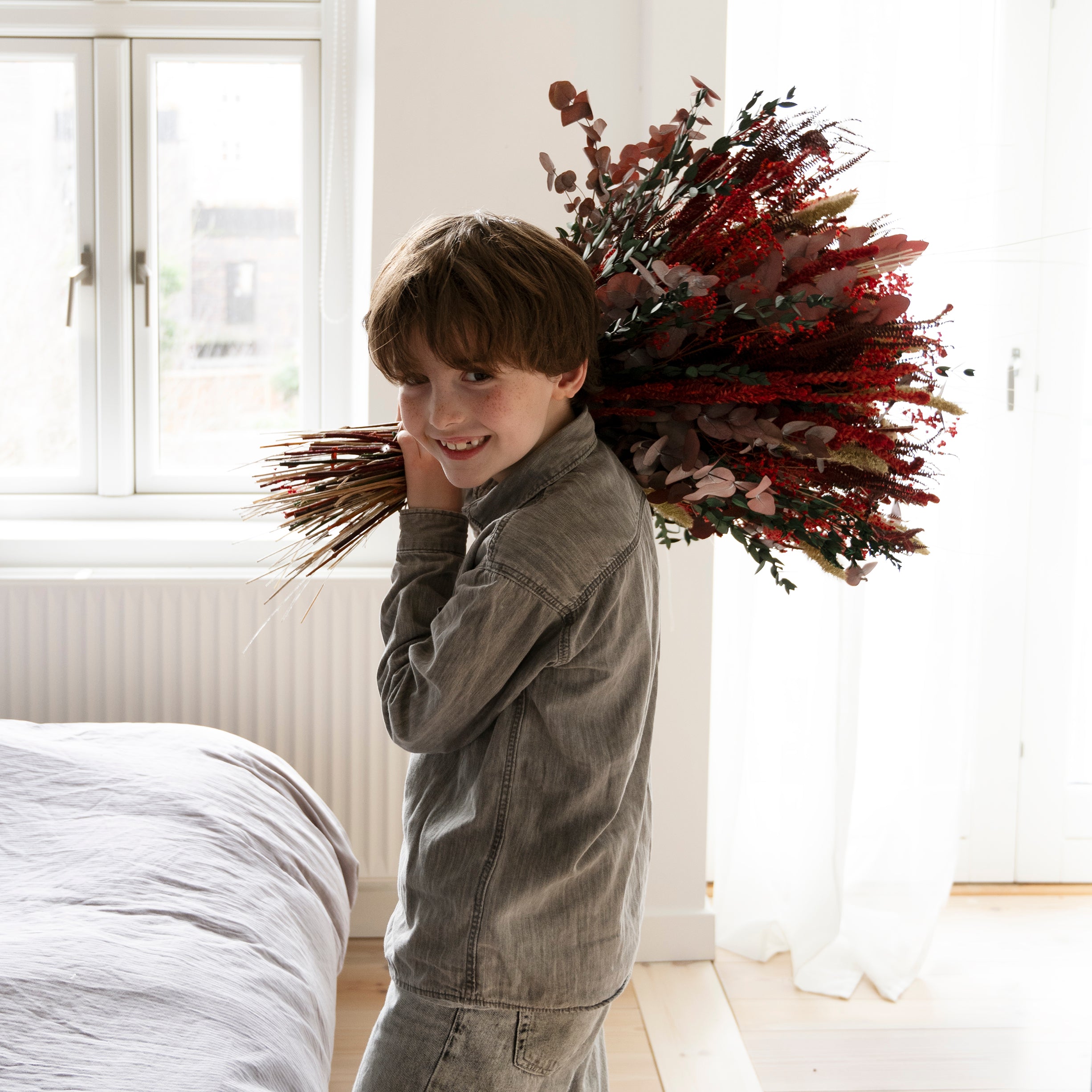 Pojke håller i en röd blombukett som han ska ge sin mamma på morsdag