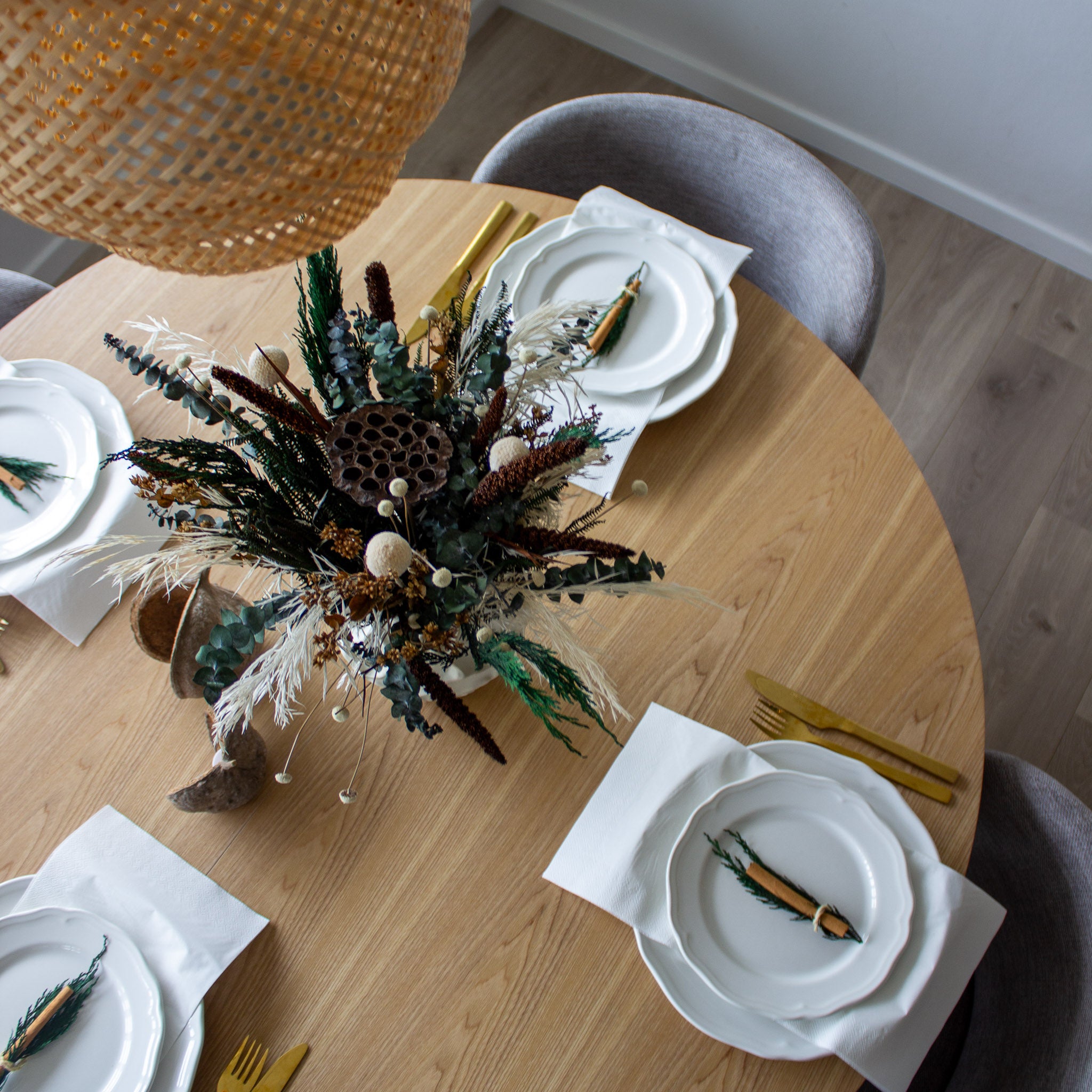 En buket i varme brun-grønne nuancer står på et julepyntet bord.
