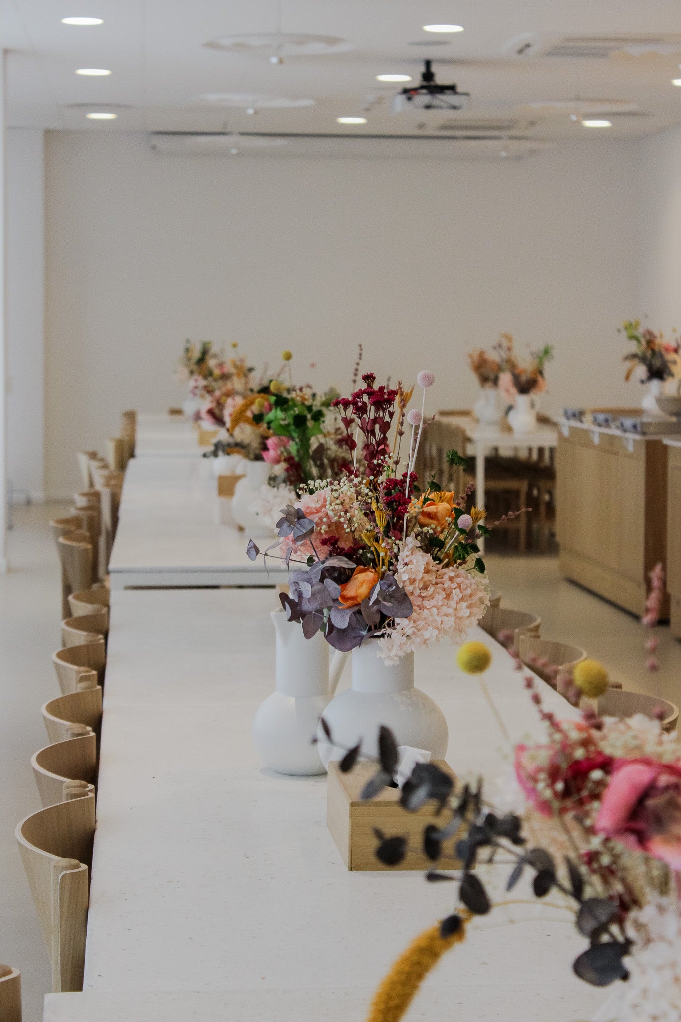 Vita långbord med vackra, färgglada blombuketter i vita vaser