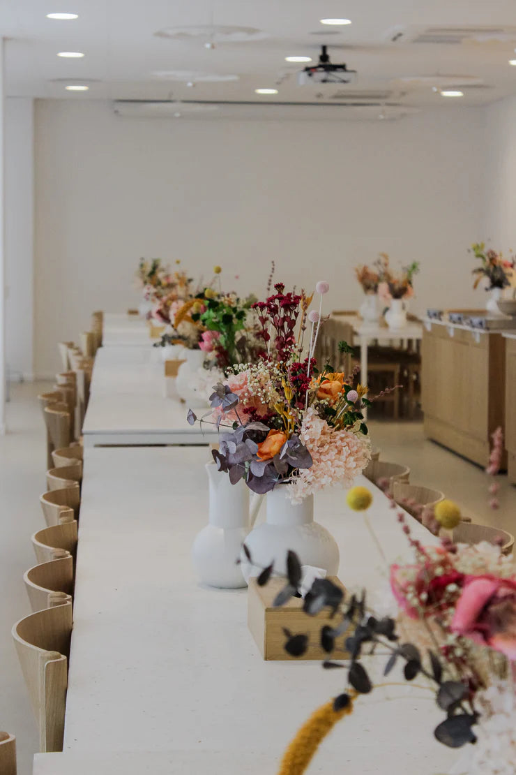 Vita långbord som dekorerats med färgglada blombuketter i vita vaser