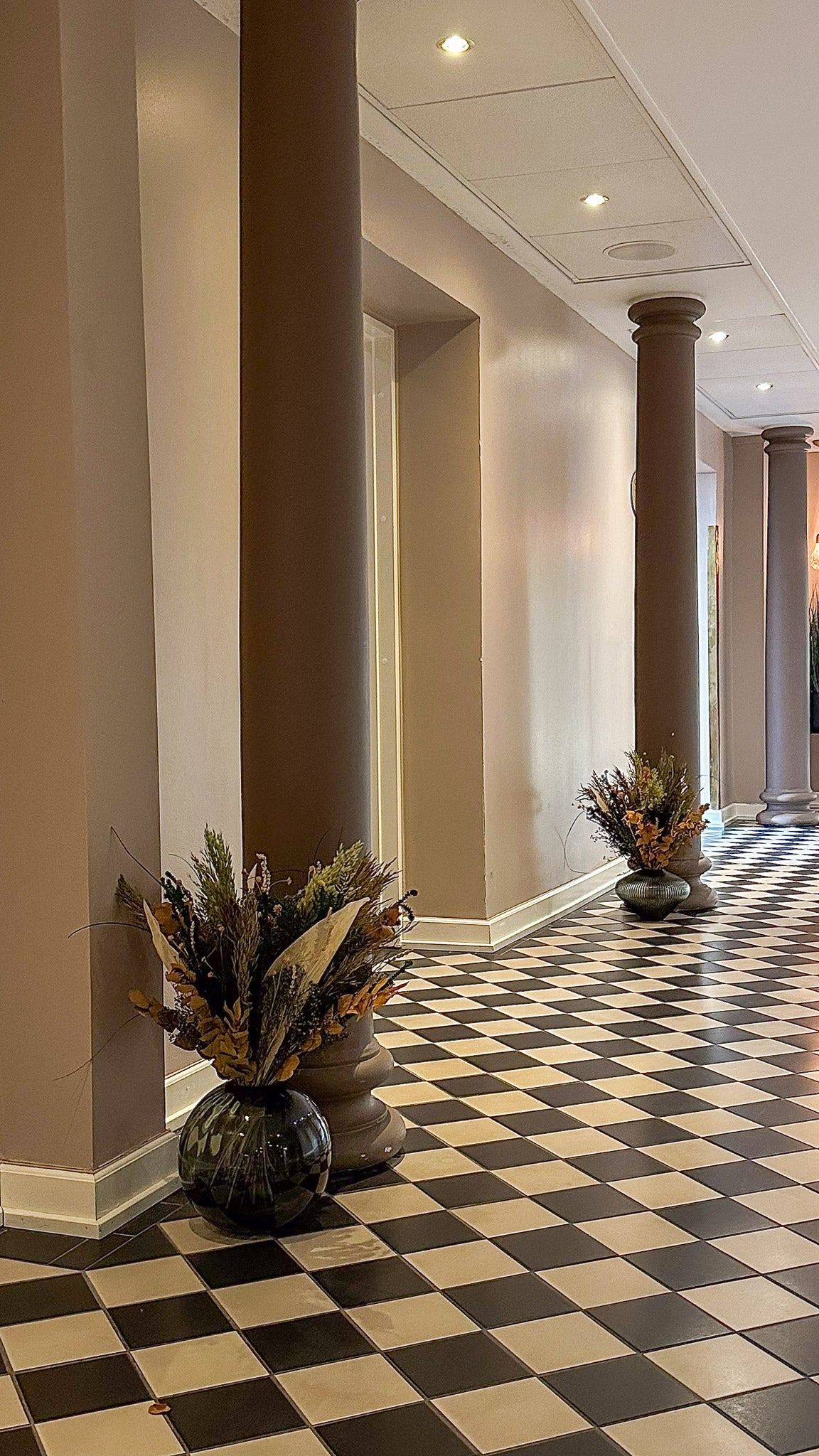 I hotellets opholdsområder står imponerende store vaser med blomsterbuketter i varme nuancer.